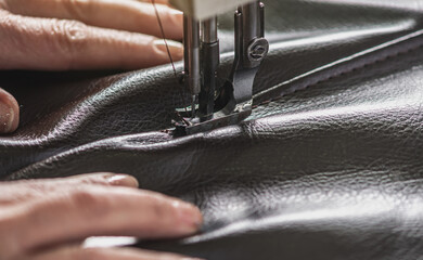 Wall Mural - Women's hands in the process of sewing on professional equipment. Sewing leather in production. Close-up