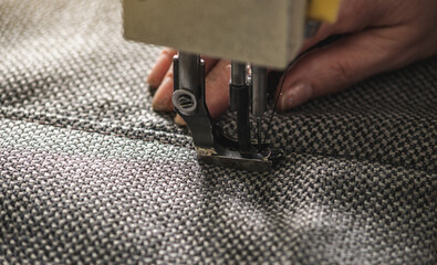 Wall Mural - Women's hands in the process of sewing on professional equipment. Sewing fabric in production. Close-up