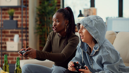 Canvas Print - Multiethnic team of women playing video games online on television console, having fun with gaming competition. Cheerful people using controller to play challenge together. Handheld shot.