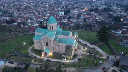 Wall Mural - Aerial view of reconstructed building of Bagrati Cathedral in Kutaisi on background with spring cityscape at dusk. Masterpiece of medieval Georgian architecture
