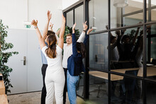 Business People With Hands Raised Standing In Circle At Modern Office