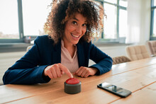 Smiling Businesswoman Touching Buzzer Button At Office