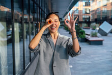 Businesswoman Gesturing OK Sign Looking Through Rolled Paper