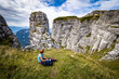 © schusterbauer.com - View of female hiker resting on the precipice near the Loser peak, looking at some prominent jags rising from the abyss, Ausseer Land, Styria, Austria