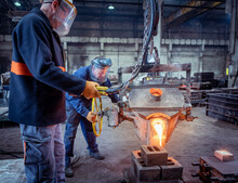 Workers Pouring Molten Metal Into Mold In Iron Foundry