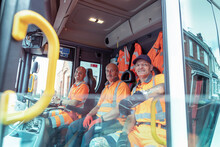 Portrait Of Refuse Collectors Sitting In Refuse Truck