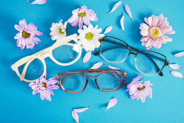 Wall Mural - trendy eyeglasses and flowers on blue background