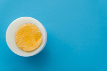 Poster - Close up view of cut boiled egg on blue background.