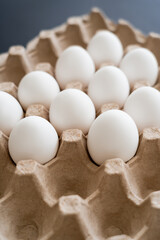 Poster - Natural chicken eggs in carton tray on blurred grey background.