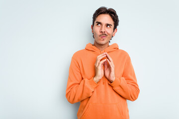 Wall Mural - Young hispanic man isolated on blue background making up plan in mind, setting up an idea.