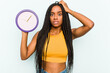 © Asier - Young African American woman holding a clock isolated on blue background being shocked, she has remembered important meeting.