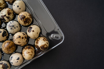 Wall Mural - Top view of quail eggs in plastic tray isolated on black.