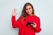 © Asier - Young caucasian gamer woman holding a game controller isolated on blue background smiling cheerful showing number five with fingers.