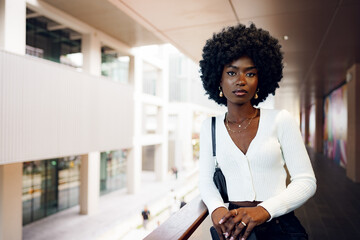 Wall Mural - Portrait of young african woman with afro hairstyle standing at balcony and posing.