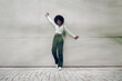 © fotofabrika - Black woman with afro hair posing in front of a gray concrete wall