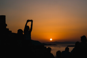 Woman traveler photographer taking photo on seascape sunset in a tour trip. Nature landscape twilight with people.