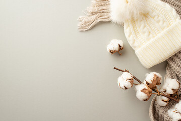 Winter concept. Top view photo of knitted bobble hat cozy scarf and cotton branch on isolated pastel grey background with empty space