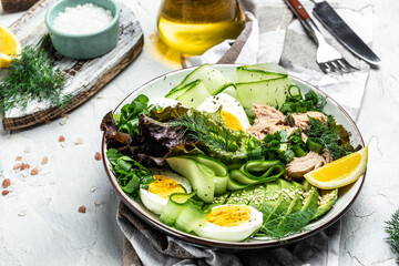 Poster - Tuna vegetable vegetarian buddha bowl avocado, egg, cucumber and fresh salad on a light background. top view