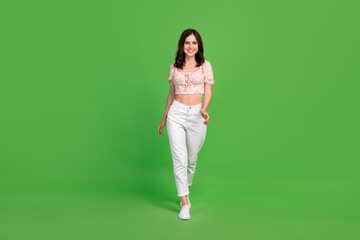 Sticker - Full size photo of gorgeous incredible woman with curly hairdo wear white trousers blouse walking isolated on green color background