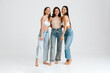 © Drobot Dean - Three young smiling women hug and pose in studio isolated