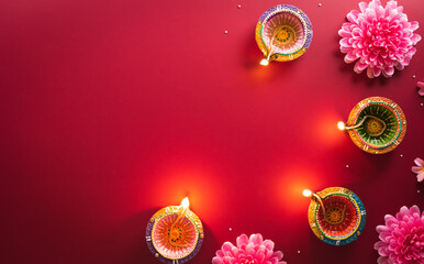 Happy Diwali - Clay Diya lamps lit during Diwali, Hindu festival of lights celebration. Colorful traditional oil lamp diya on red background