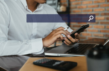 Male businessman clicking internet search page on computer and smart phone touch screen in the office.