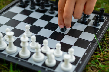 Child playing chess on the lawn. Little boy makes first move and developing chess strategy, play board game with friend.