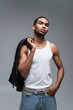 Leinwandbild Motiv muscular young african american man in tank top holding leather jacket isolated on grey.