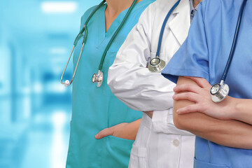 Wall Mural - Three Doctors with stethoscope in standing on blurred green background of hospital hall. Medical team. Group of doctors and nurses. Innovative technologies in science and medicine, medical development