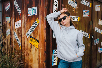 Wall Mural - City portrait of beautiful young female wearing gray blank hoodie and blue jeans with space for your logo or design. Mockup for print