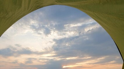 Canvas Print - View on dramatic cloudy sunset sky from tent on summer evening.