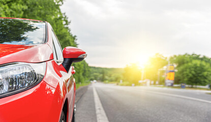 Wall Mural - Red car on the road at sunset.