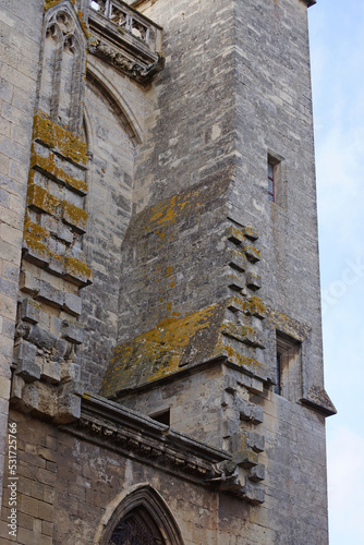 Fototapete Archaisch wirkendes bemoostes Gemäuer an einer wuchtigen gotischen Kirche. Bereiche der alten Fassade bröckeln. 