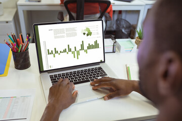 Poster - African american businessman analyzing business report over laptop at office