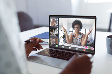 Canvas Print - Hands of african american woman discussing with multiracial coworkers on videocall over laptop