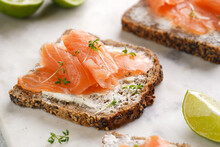 Wholewheat Bread Sandwiches With Cream Cheese And Smoked Salmon On Marble Board With Lime Slices And Sour Cream