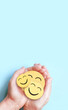 Hand holding happy smile face on blue background, Positive thinking, Mental health, World mental health day concept.