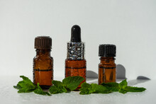 A Bottle With Essential Oil And Mint On A White Background. Essential Aroma Oil. Glass Bottle Of Peppermint Essential Oil With Fresh Green Mint Leaves, Mint Oil. Selective Focus. 