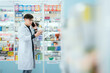 © 2B - A male pharmacist checks drug stocks in a community pharmacy. use the phone to talk