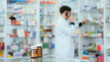 © 2B - A male pharmacist checks drug stocks in a community pharmacy. use the phone to talk