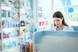 © 2B - A female pharmacist checks drug stocks in a community pharmacy.