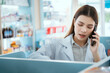 © 2B - A female pharmacist checks drug stocks in a community pharmacy. use the phone to talk