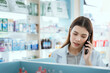 © 2B - A female pharmacist checks drug stocks in a community pharmacy. use the phone to talk