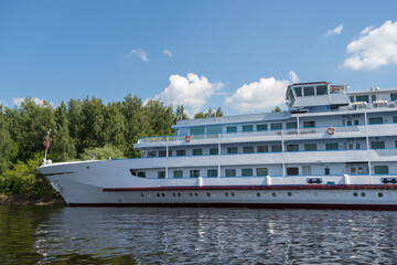 Wall Mural - A huge white 4-deck tourist ship is moored to the river bank.