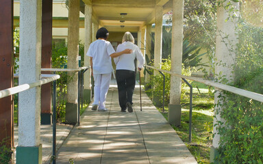 Sticker - Asian doctor helping elderly retired woman with walker stick in the hospital yard. Rehabilitation concept