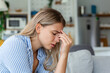 © Graphicroyalty - Portrait of a young woman sitting on the couch at home with a headache and pain. Beautiful woman suffering from chronic daily headaches. Sad woman holding her head because sinus pain