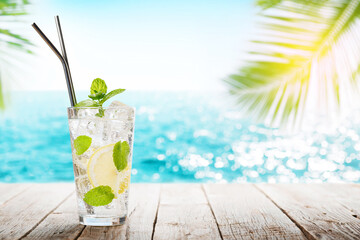 Mojito cocktail on wooden table in front of sunny sea