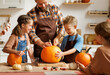 © JenkoAtaman - Happy family mother, father and kids  to remove pulp from from pumpkin while carving jack o lantern with family