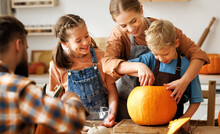 Happy Family Mother, Father And Kids  To Remove Pulp From From Pumpkin While Carving Jack O Lantern With Family