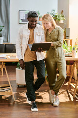 Aufkleber - Young blond smiling businesswoman in casualwear helping her colleague with presentation during teamwork over new project in office